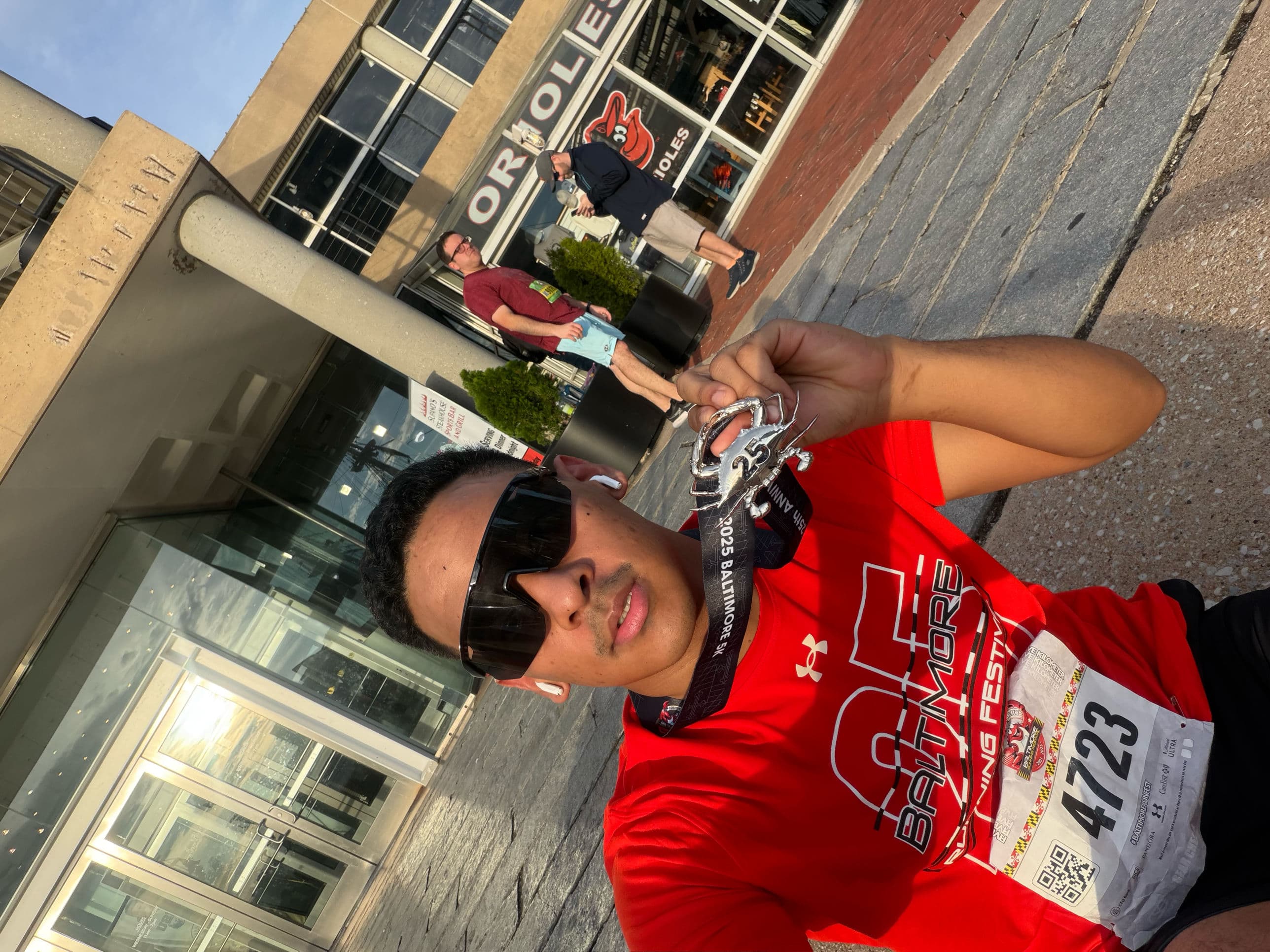 Mingma holding the Baltimore Running Festival 5K crab medal